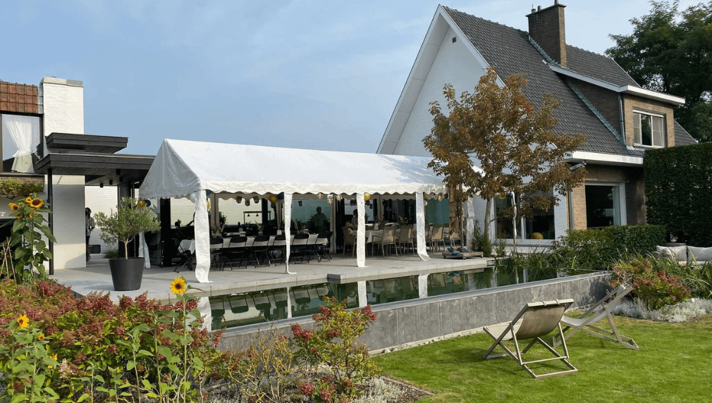 White party tent next to a modern house with garden and swimming pool.
